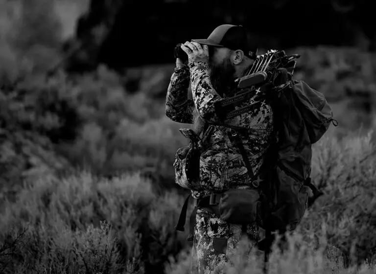 bowhunter scanning the Nevada desert with binoculars