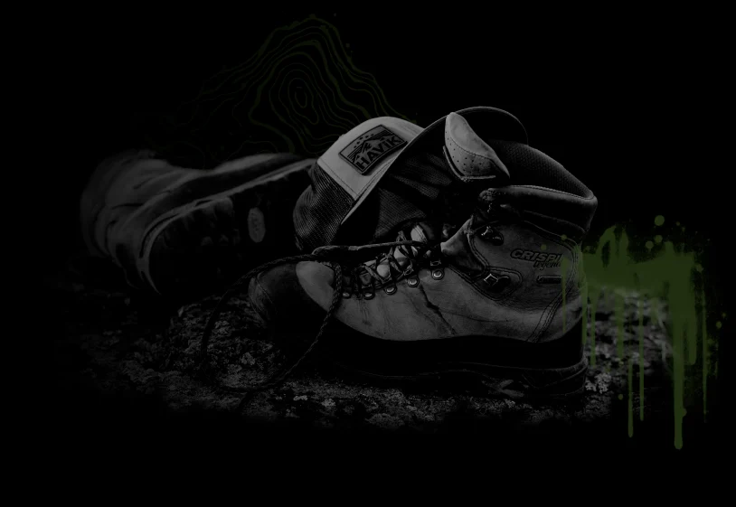 Worn hiking boots and a HAViK trucker hat on rocky ground