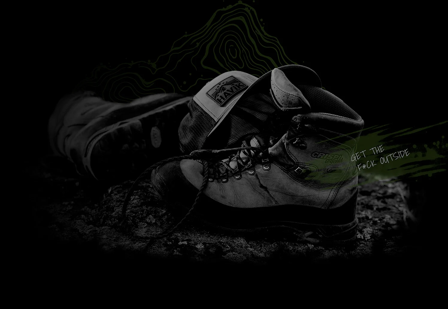 Worn hiking boots and a HAViK trucker hat on rocky ground